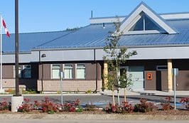 A building with a blue roof and flowers in front of it.