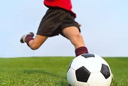 A person kicking a soccer ball on the field.