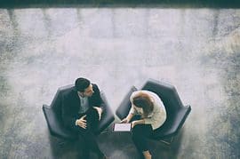 Two people sitting in chairs talking to each other.