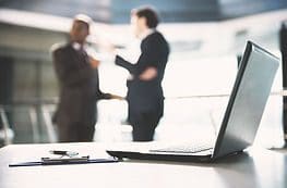 Two people standing in front of a laptop.