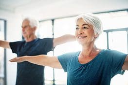 A woman and man doing yoga in the gym.