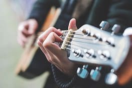 A person holding a guitar in their hand.