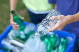 A person holding a bottle of water over some plastic.