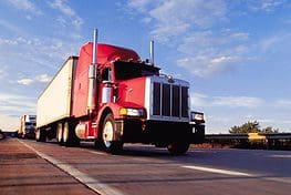 A red truck is driving down the road.