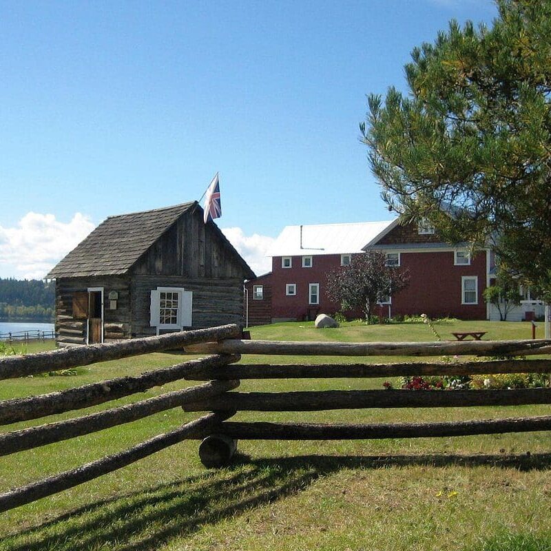 A barn and some buildings in the grass.